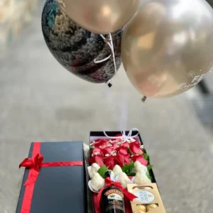 Caja con rosas, fresas con chocolate, botella de Bailey's y globos con helio