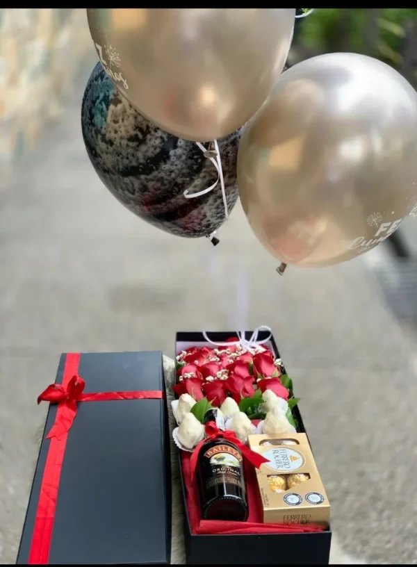 Caja con rosas, fresas con chocolate, botella de Bailey's y globos con helio